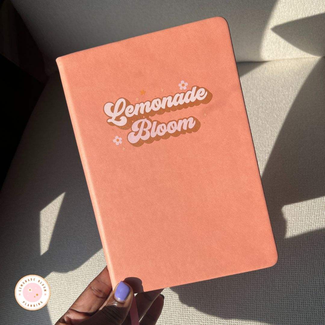 Lemonade Bloom Retro 70s pink goal tracker planner with soft cover and playful font design.